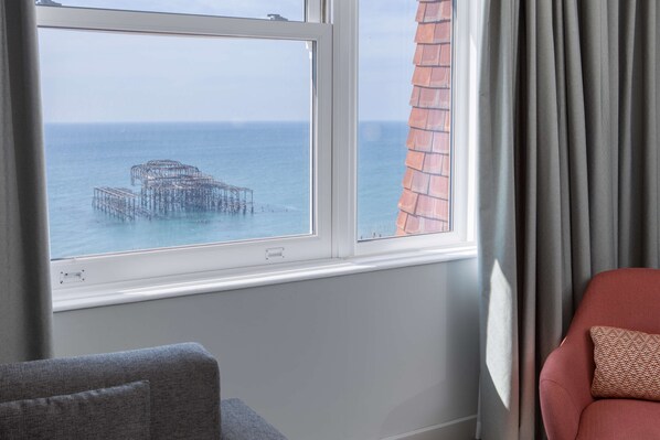 Una habitación con vista al mar y una estructura de muelle a través de una ventana.