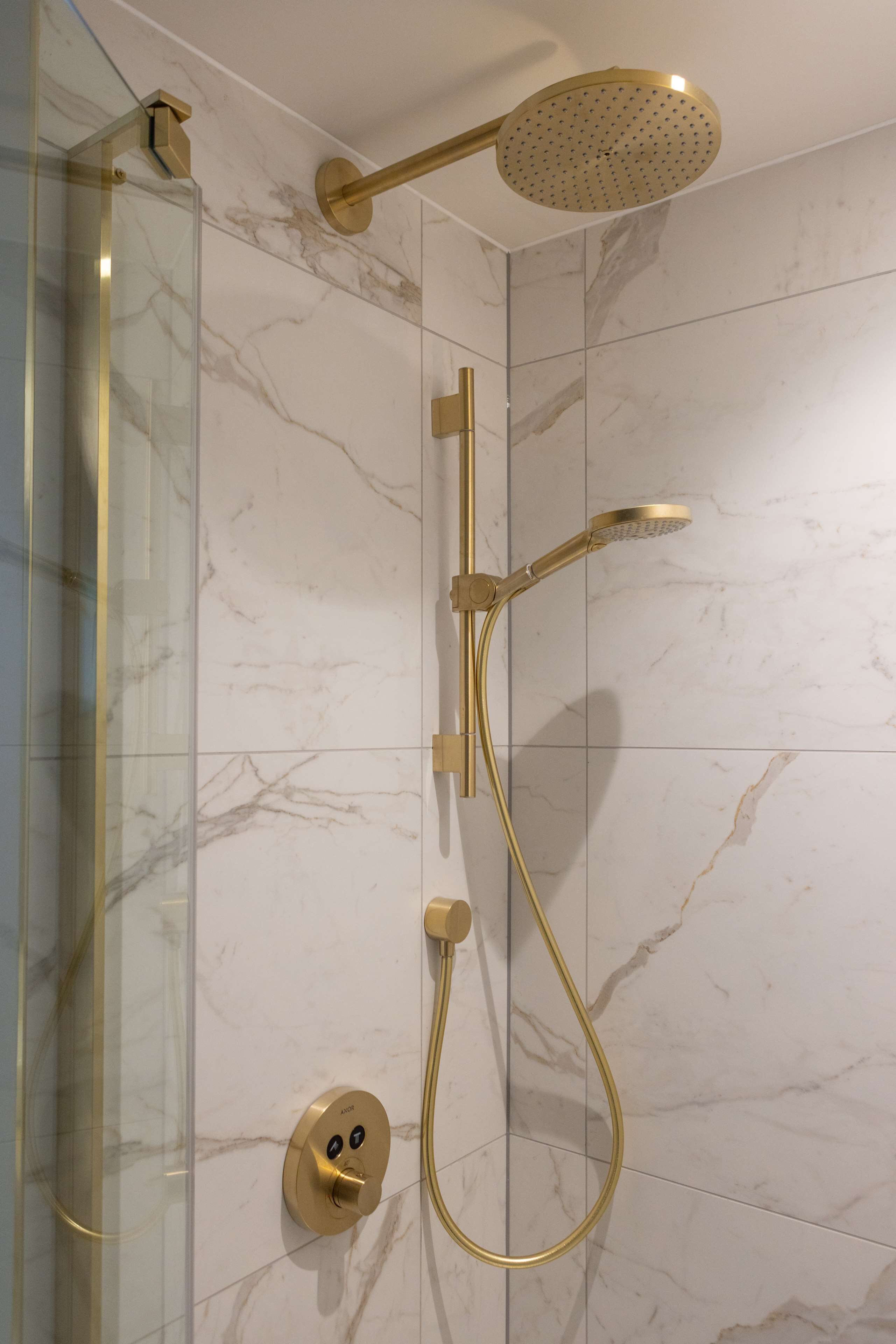 Ducha moderna con cabezal y mandos dorados.
