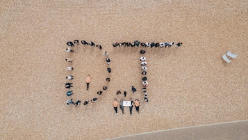An aerial view of a beach with people arranged in the shape of the letters "DT".