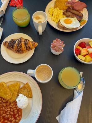 A breakfast table with various dishes including eggs, sausages, toast, and fruit. - DoubleTree by Hilton Brighton Metropole (Brighton)