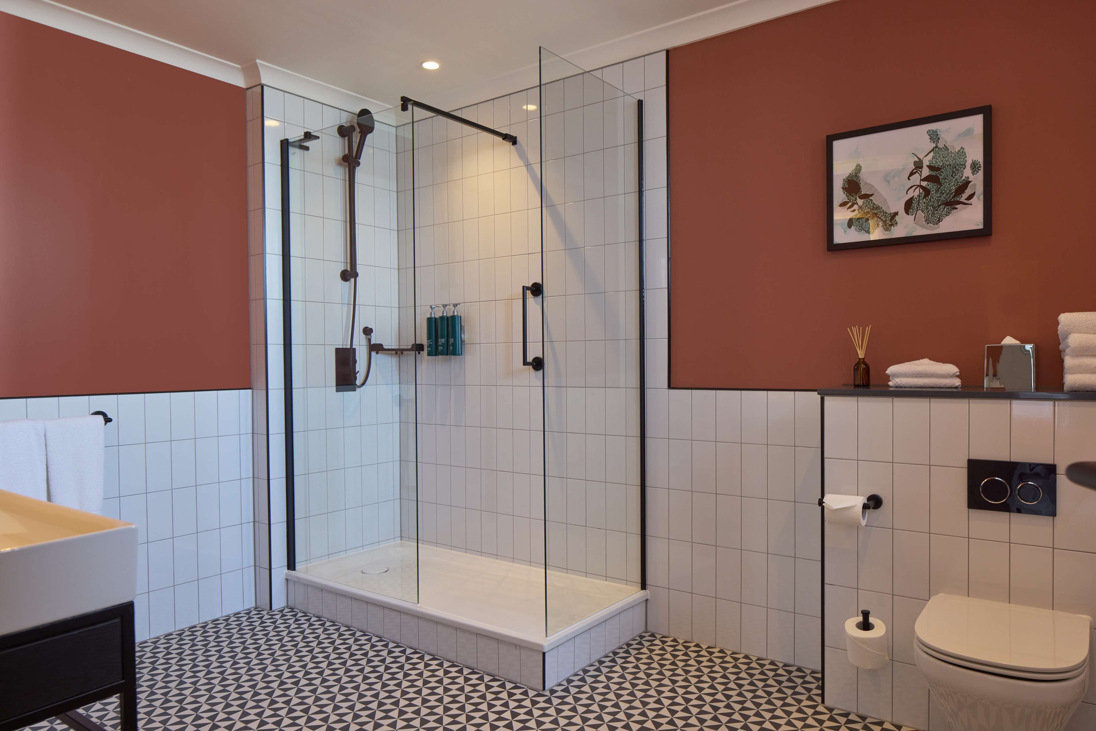 A modern bathroom with a glass-enclosed shower, a toilet, and a sink.