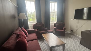 A living room with a sofa, armchairs, a coffee table, and a TV.