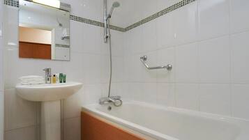 Un baño con lavamanos blanco, espejo y bañera.