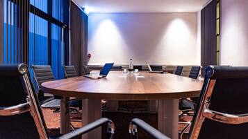 A conference room with a round table, black leather chairs, and a laptop on the table.