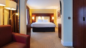 A hotel room with a large bed, two bedside lamps, a nightstand, and a chair. - Avisford Park Hotel (Arundel)