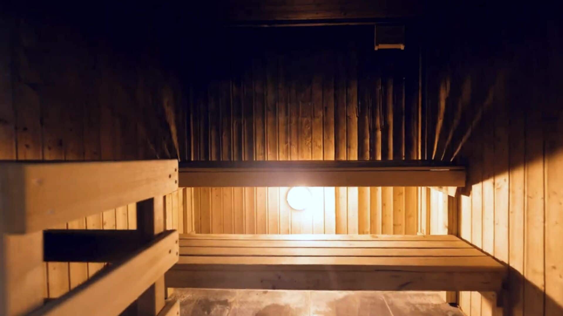 A wooden sauna with benches and a visible light source.