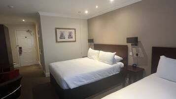 A hotel room with two beds, a desk, a chair, and a door.