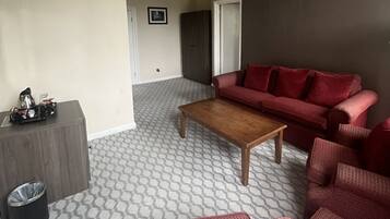 A living room with a patterned carpet, a wooden coffee table, and a red sofa set.