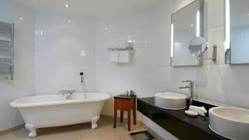 Een moderne badkamer met een vrijstaand bad, twee wastafels en een grote spiegel.