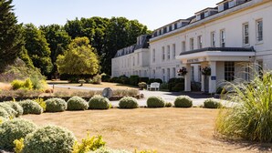 A large, white building with a garden in front. There is a bench and a sign that says "Aylesford Park." - Avisford Park Hotel (Arundel)