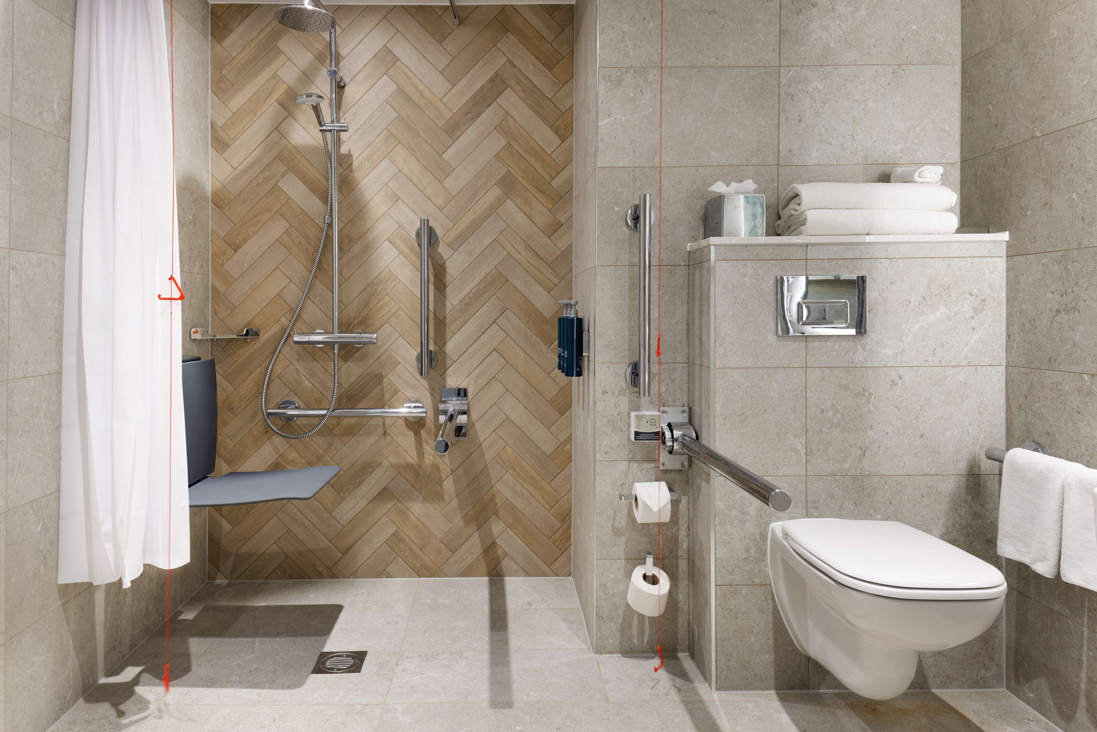 A modern bathroom with a shower, toilet, and sink.