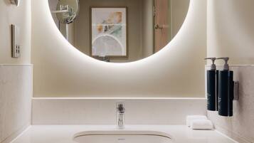 Un baño moderno con un espejo redondo, un lavamanos y dos toallas.