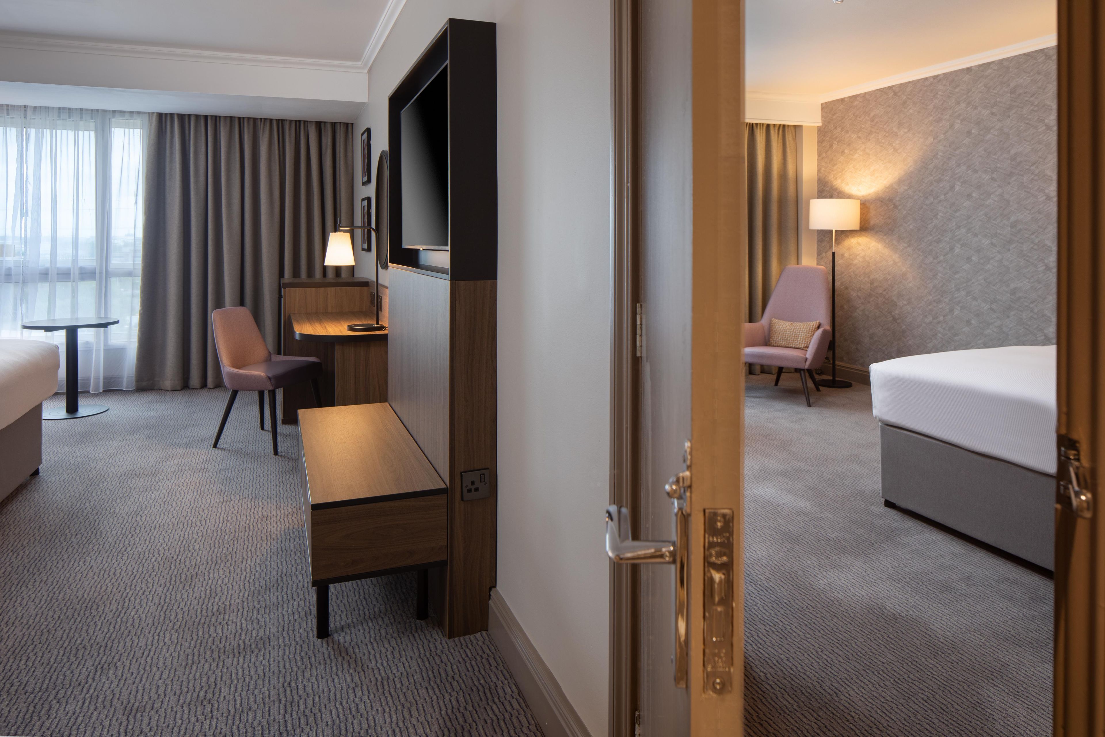 Ein Hotelzimmer mit einem Bett, einem Schreibtisch, einem Stuhl, einem Fernseher und einer Lampe.