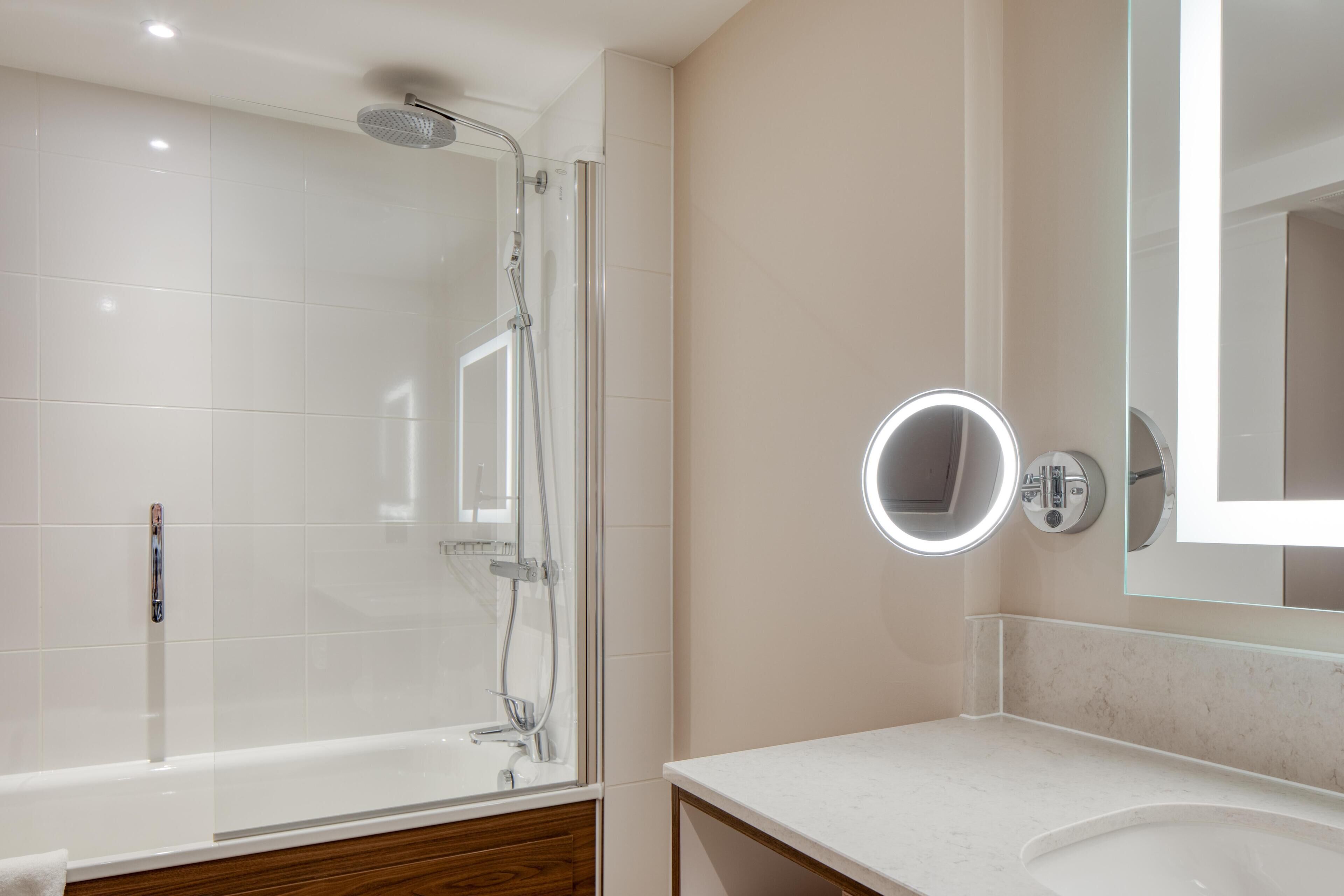 Een moderne badkamer met een douchecabine van glas, een wastafel met spiegel en een bad.