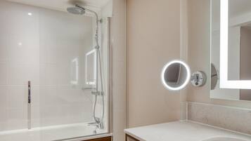 Een moderne badkamer met een douchecabine van glas, een wastafel met spiegel en een bad.