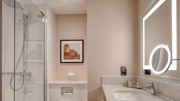 A modern bathroom with a glass-enclosed shower, a large mirror, and a marble sink.