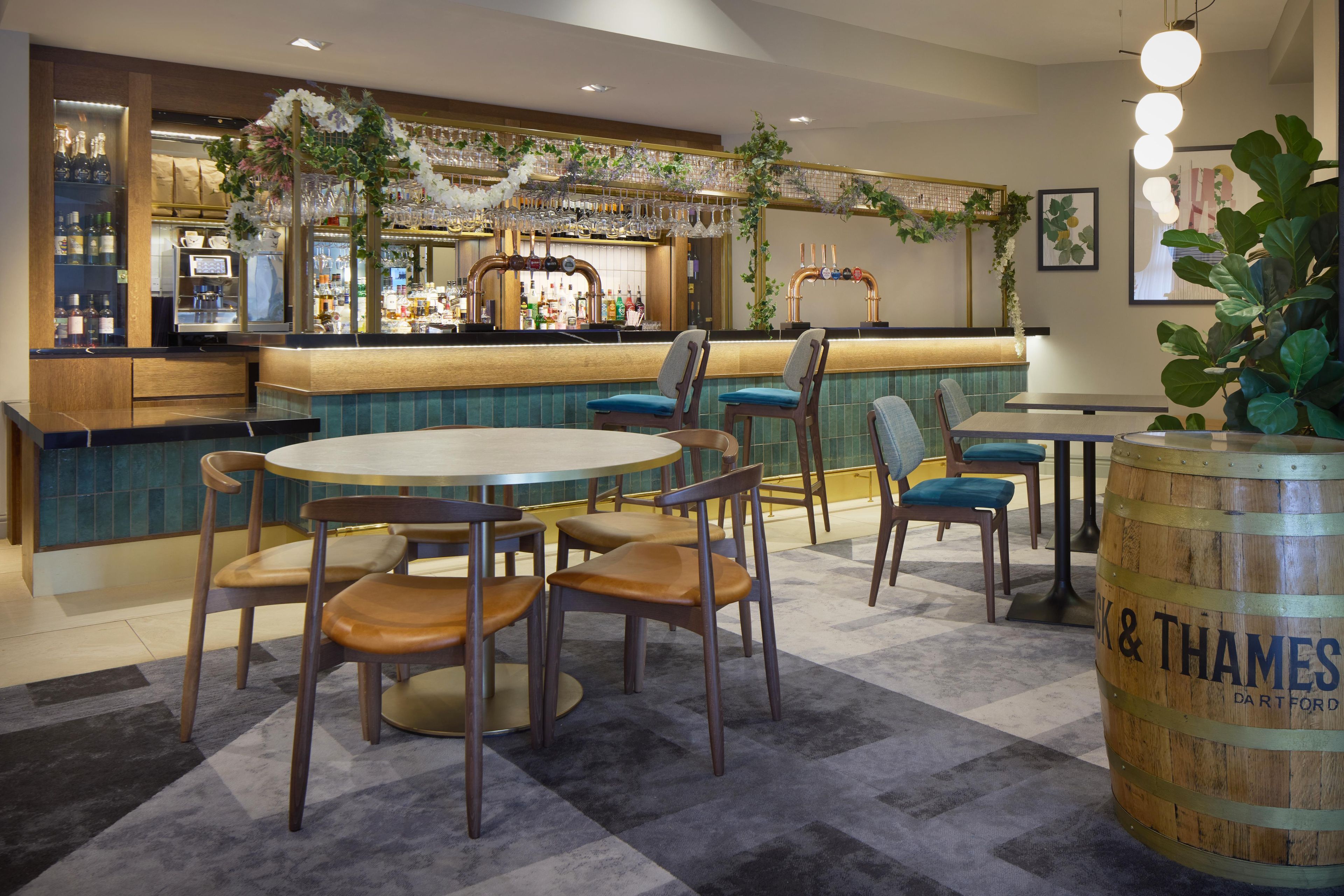 A bar area with a round table and chairs, a counter with a beer tap, and a large barrel labeled 'Thames & Dartford'.