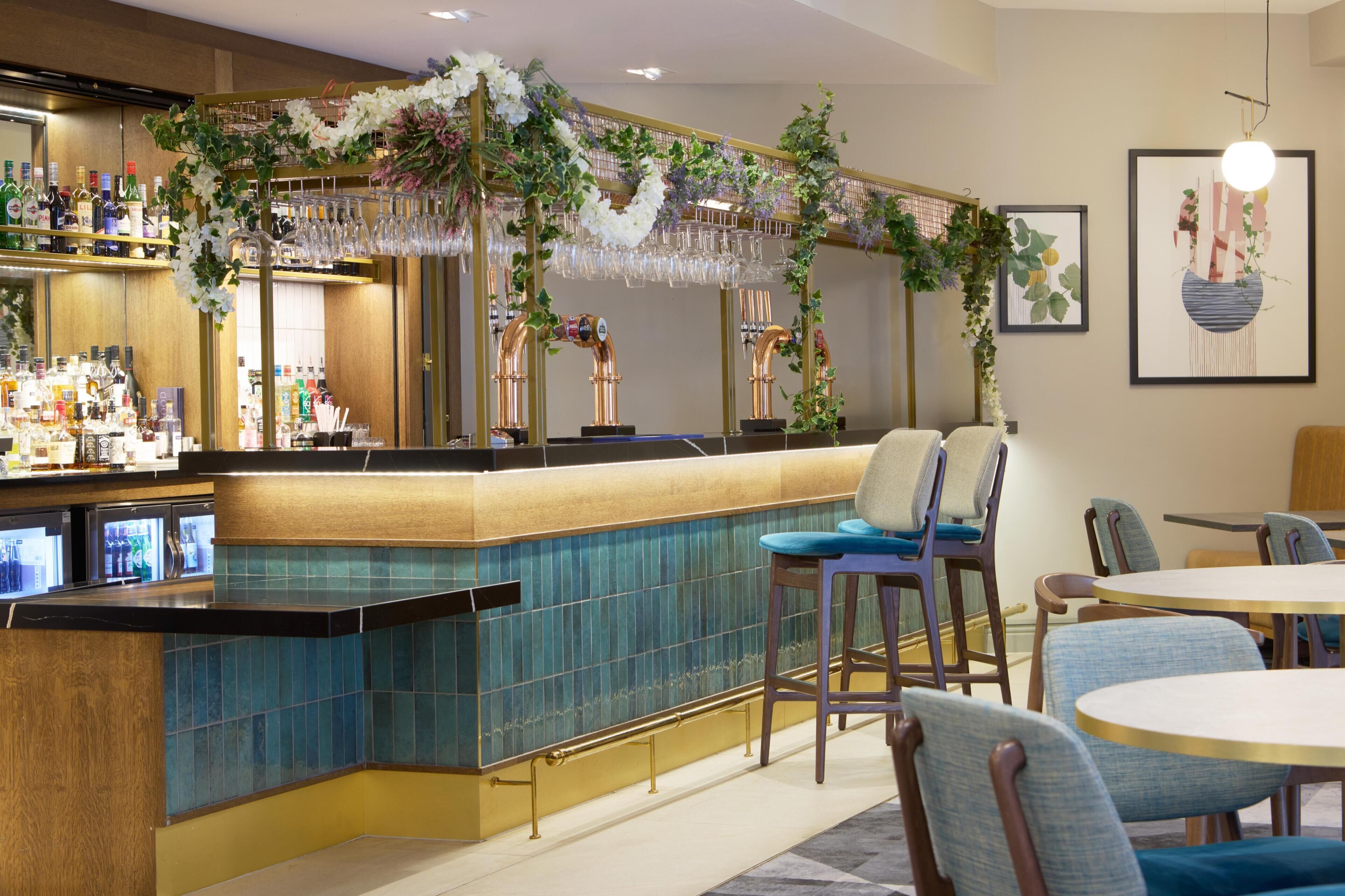 A bar area with a counter, bar stools, and a seating area with round tables and chairs.