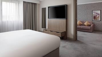 Una habitación de hotel con cama, televisión, cómoda, sofá y un cuadro en la pared.