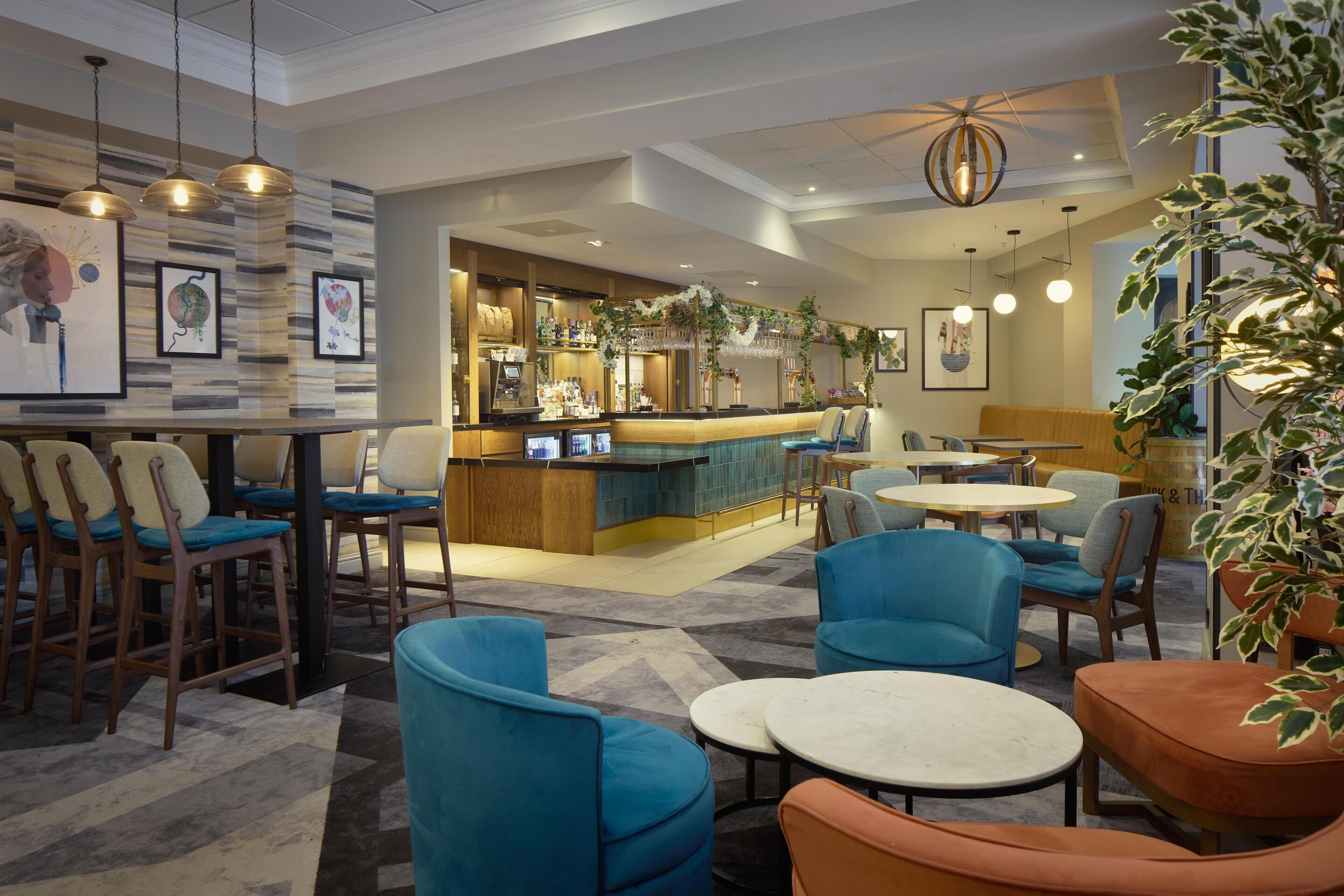 A hotel lobby with a bar area, seating arrangements, and a large plant.