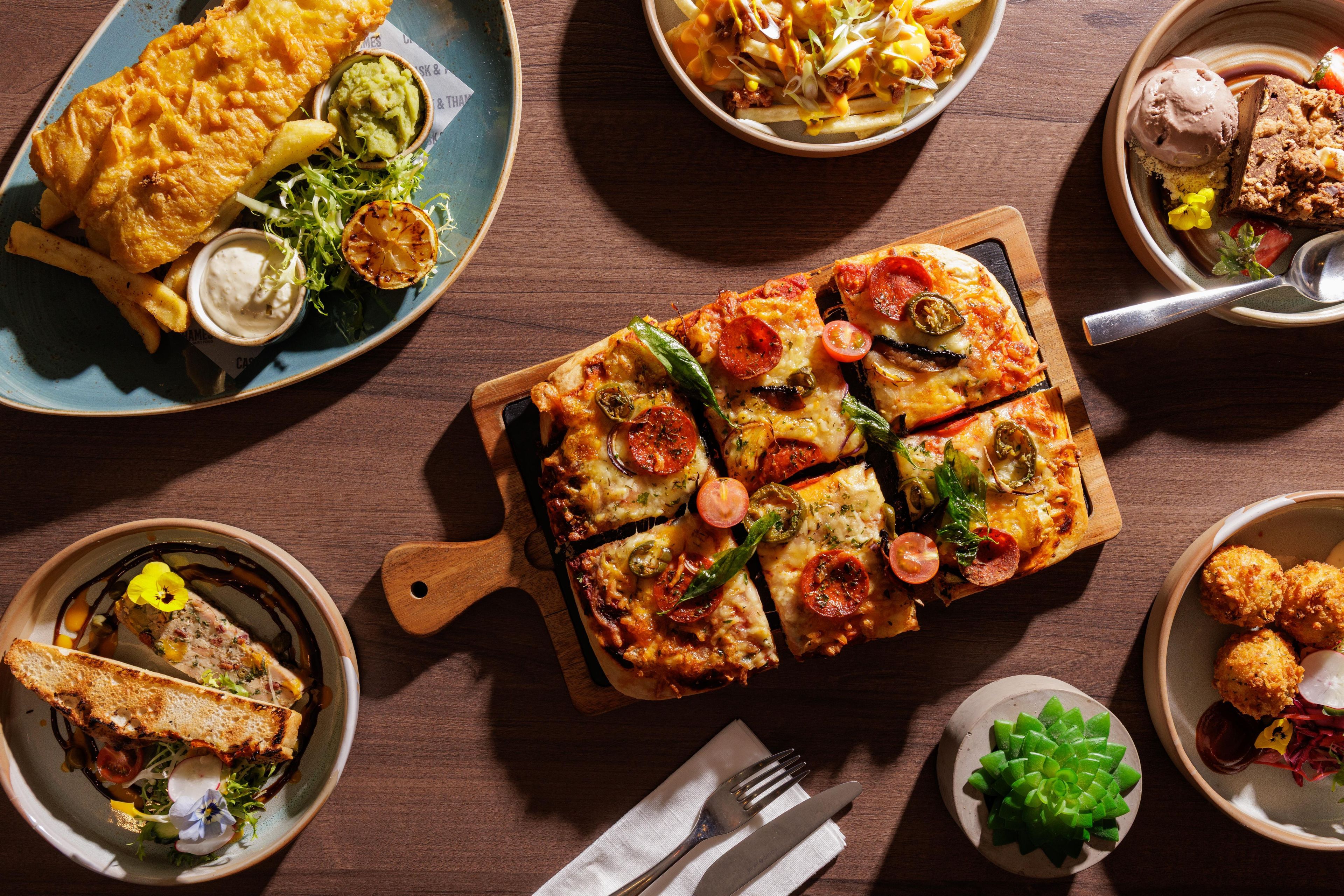 A variety of dishes including a pizza, fries, and a sandwich, suggesting a restaurant setting.