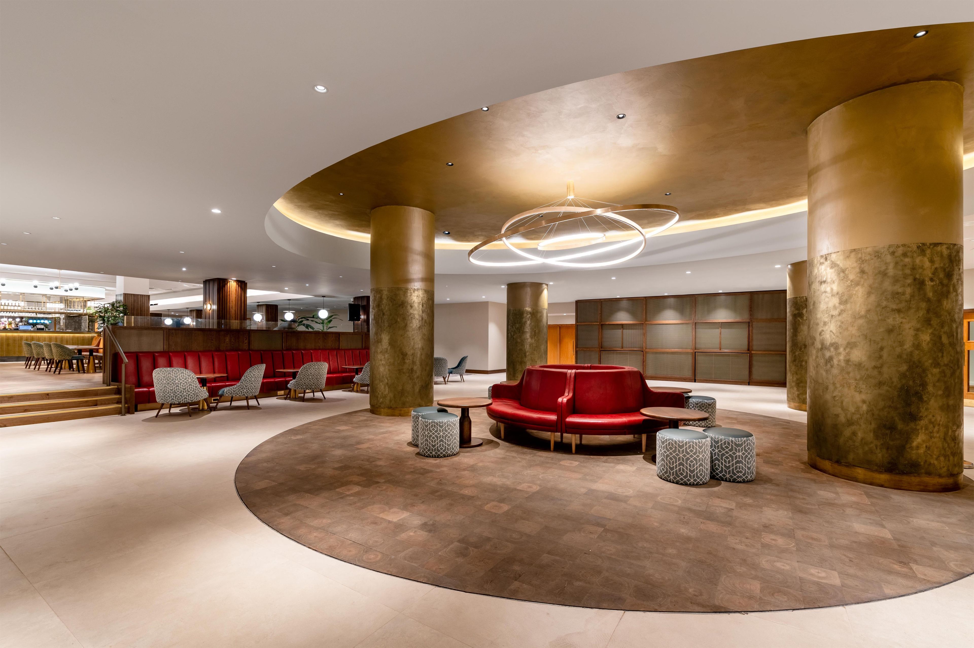 A spacious lobby with a central seating area, large pillars, and a modern ceiling design.