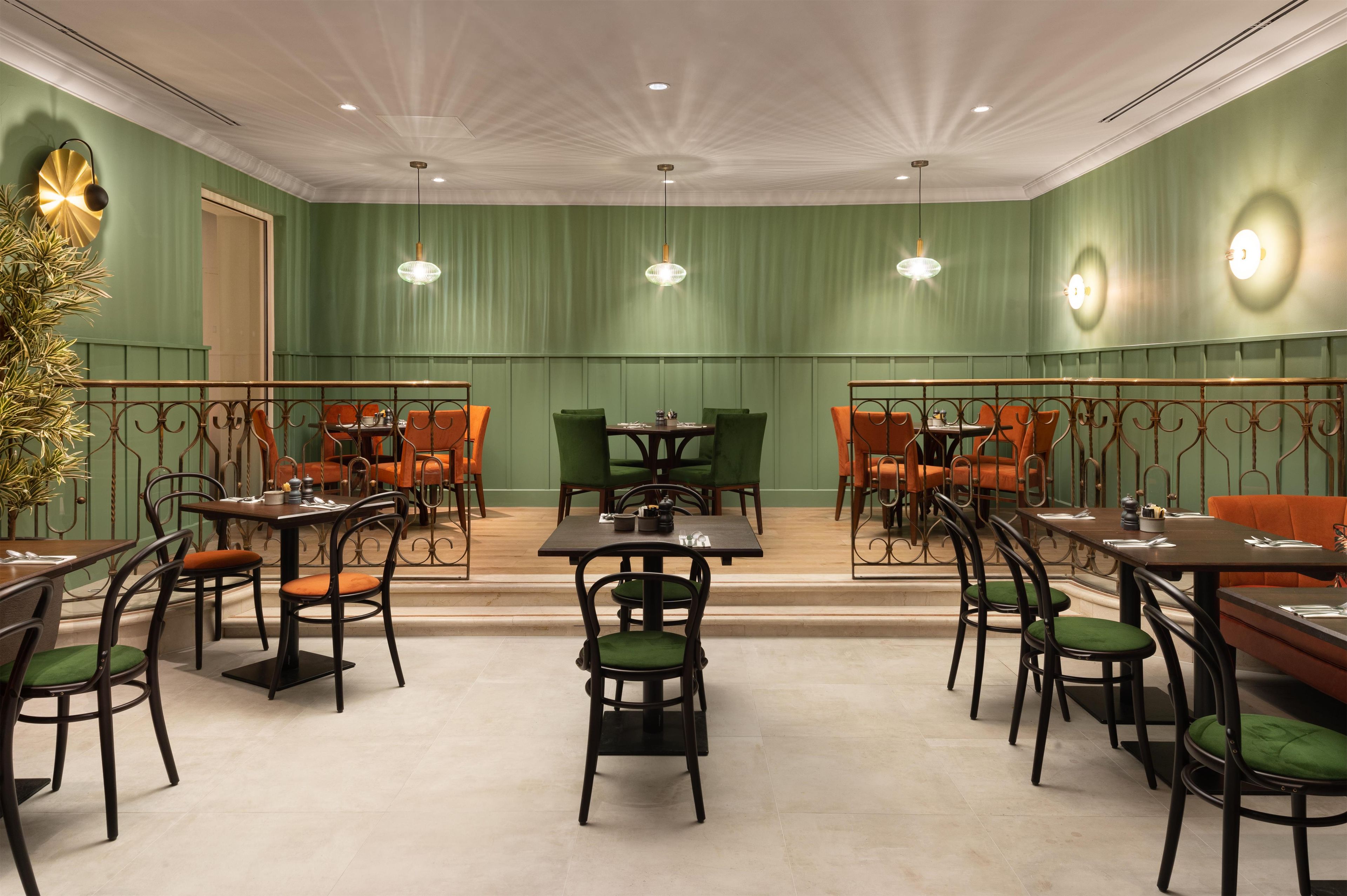 A restaurant with green walls, multiple tables, and chairs.