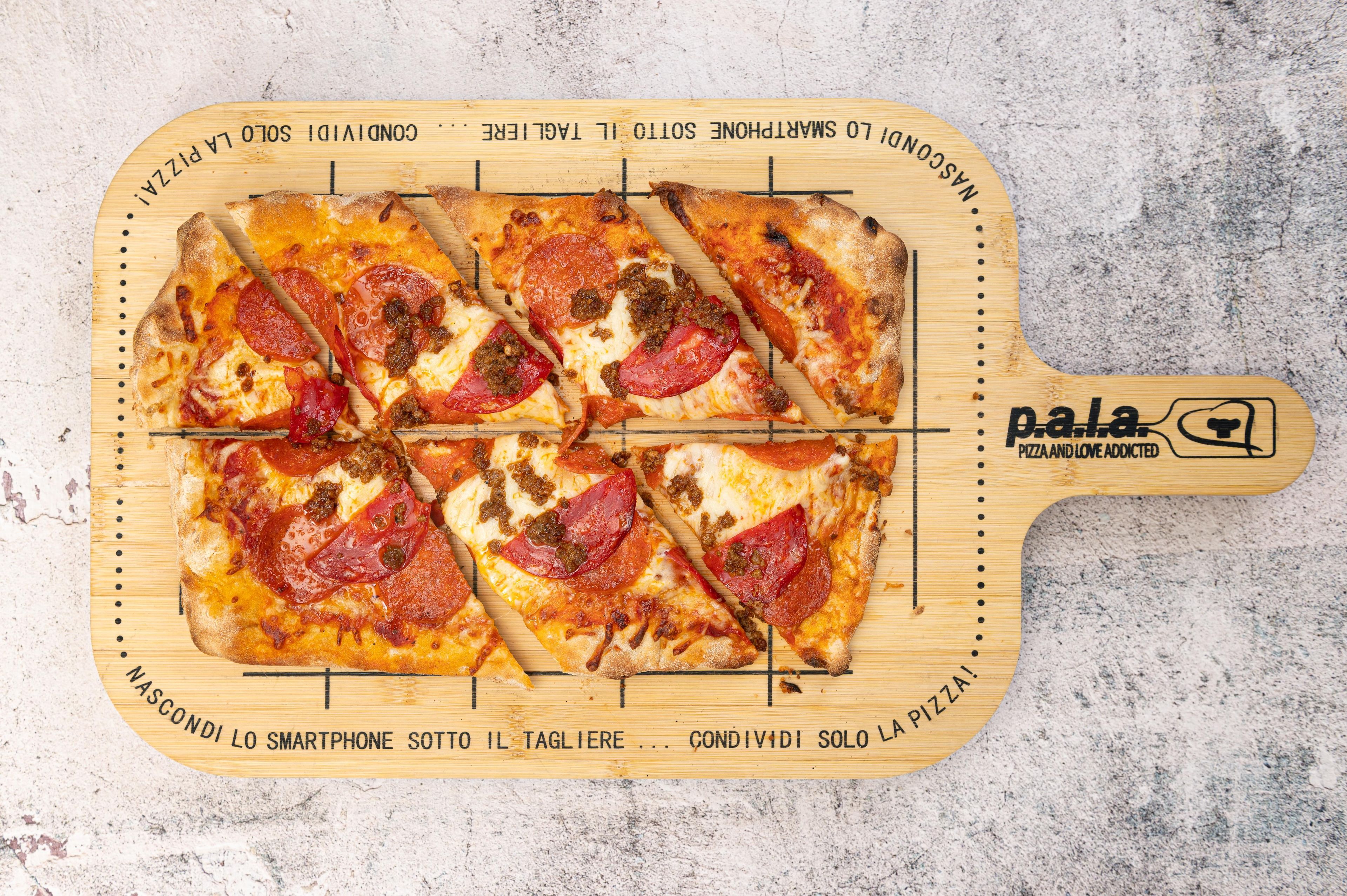 A pizza on a wooden board with text and a logo.