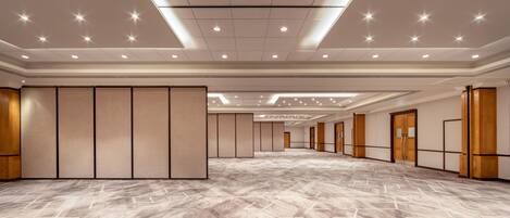 A spacious hotel room with a patterned floor, recessed ceiling lights, and wooden panel dividers.