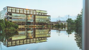 Un edificio moderno con fachada de vidrio que se refleja en aguas tranquilas.