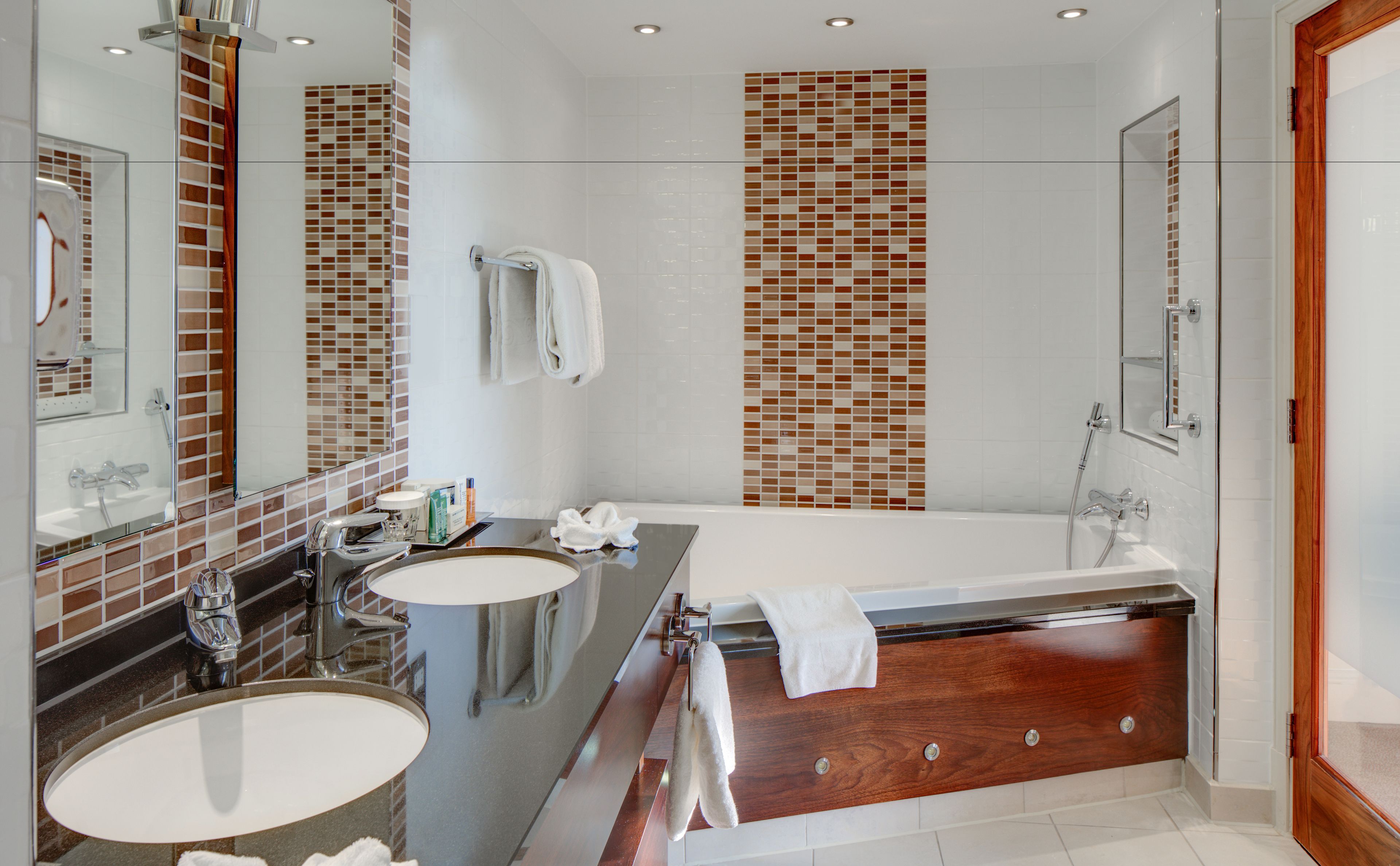 Ein modernes Badezimmer mit Badewanne, zwei Waschbecken und einem großen Spiegel.