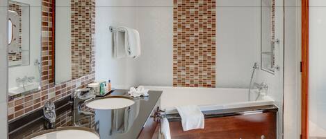 Ein modernes Badezimmer mit Badewanne, zwei Waschbecken und einem großen Spiegel.