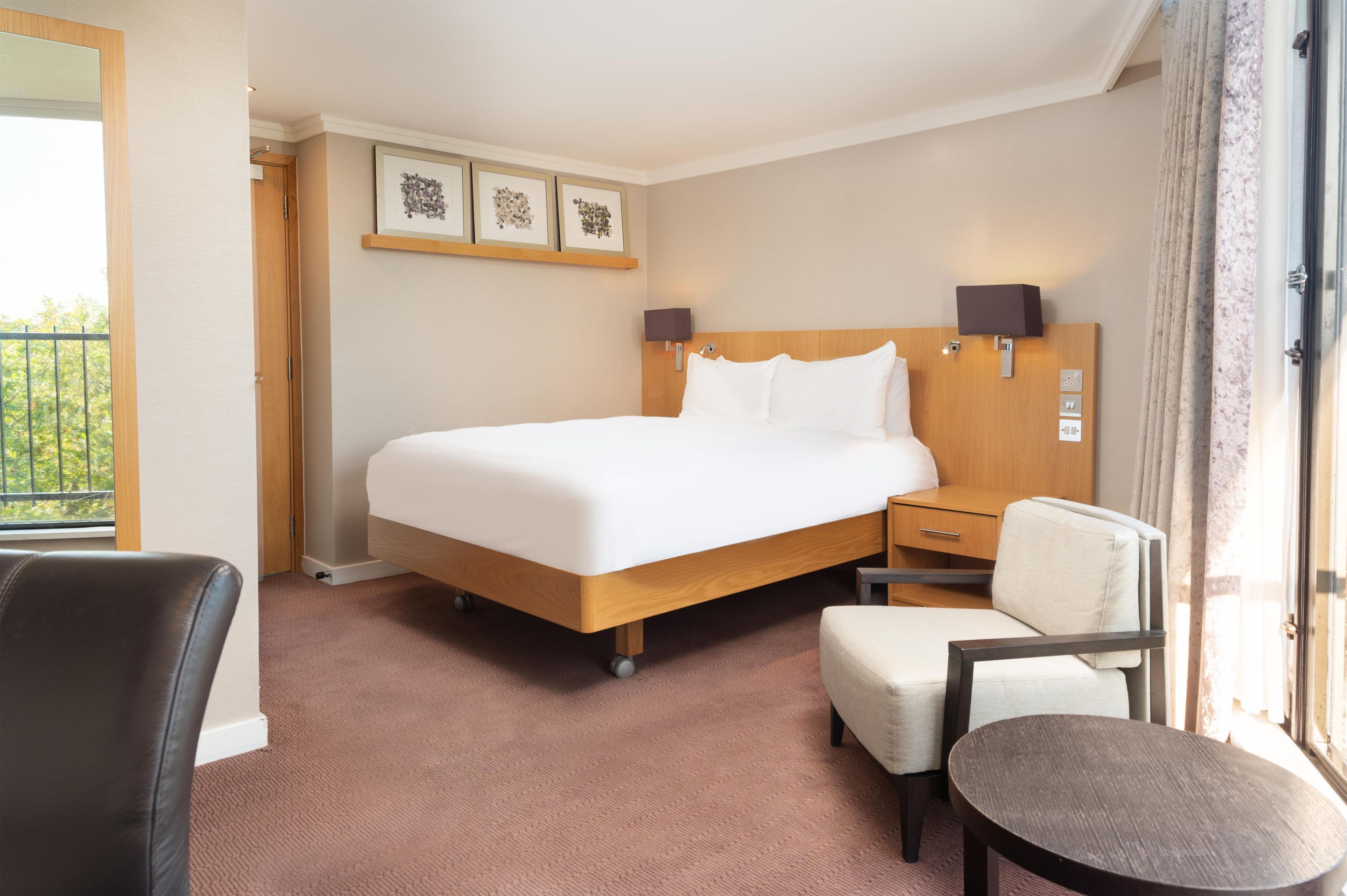 Une chambre d’hôtel avec un lit, un bureau, une chaise et une fenêtre.