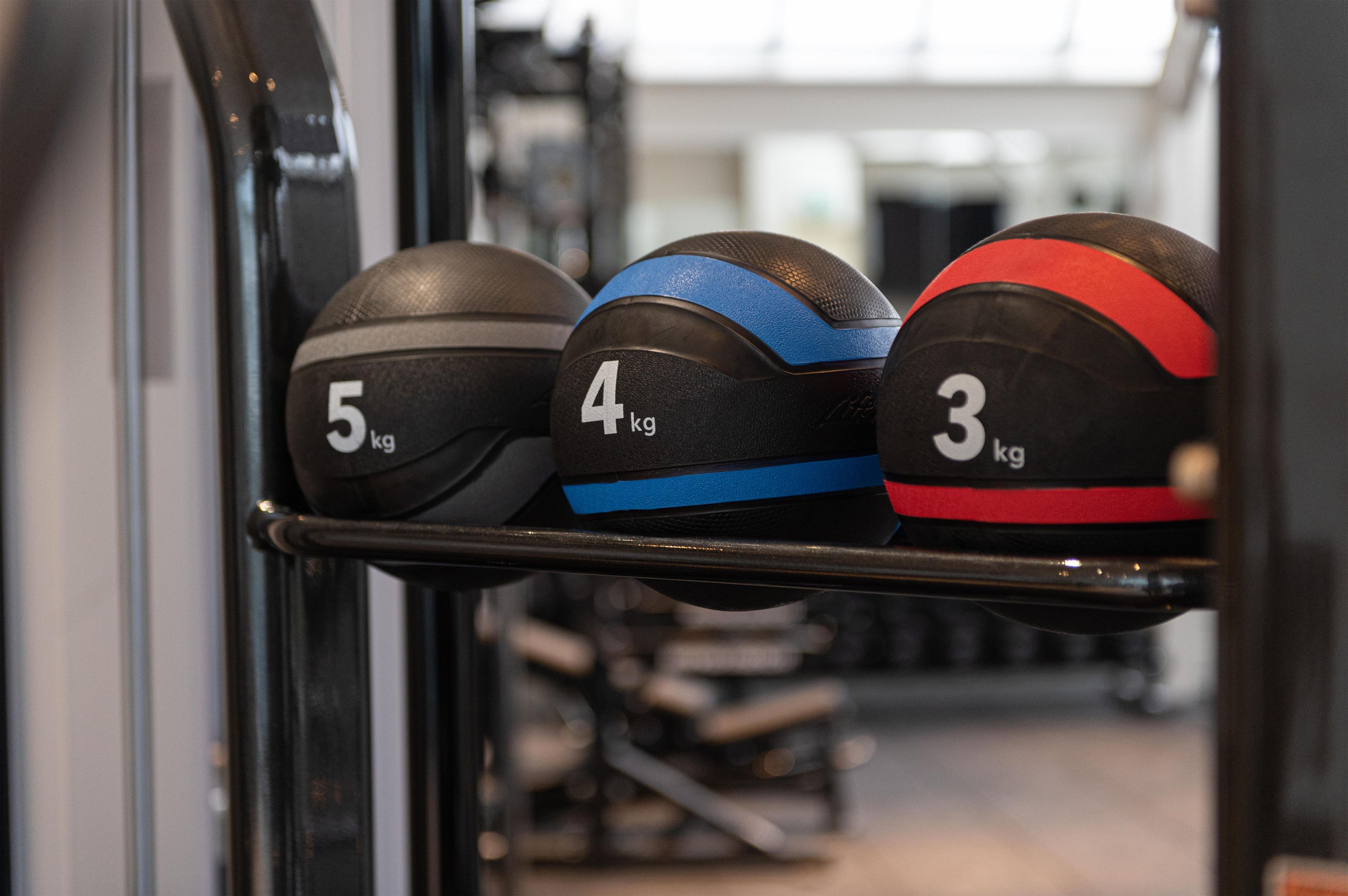 A rack with three weight plates labeled 5 kg, 4 kg, and 3 kg.