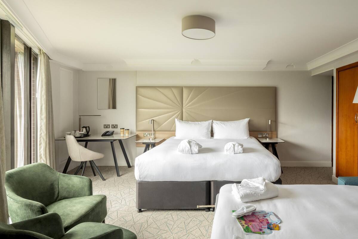 A hotel room with a bed, bedside tables, a desk, a chair, and a wardrobe.
