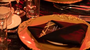 A formal dining setting with a red napkin, a gold-rimmed plate, and a glass of water.