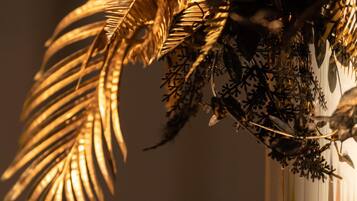A close-up of a decorative arrangement with golden leaves and a glass vase.