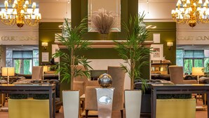 A lobby with a green wall, two chandeliers, a mirror, and a seating area with leather sofas and a coffee table. - Bromsgrove Hotel (Bromsgrove)