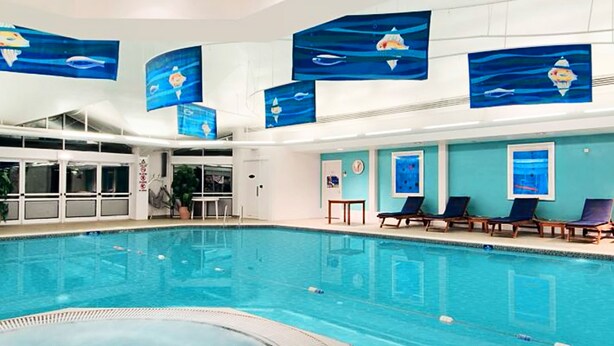 A swimming pool with lounge chairs and artwork depicting marine life. - Bromsgrove Hotel (Bromsgrove)