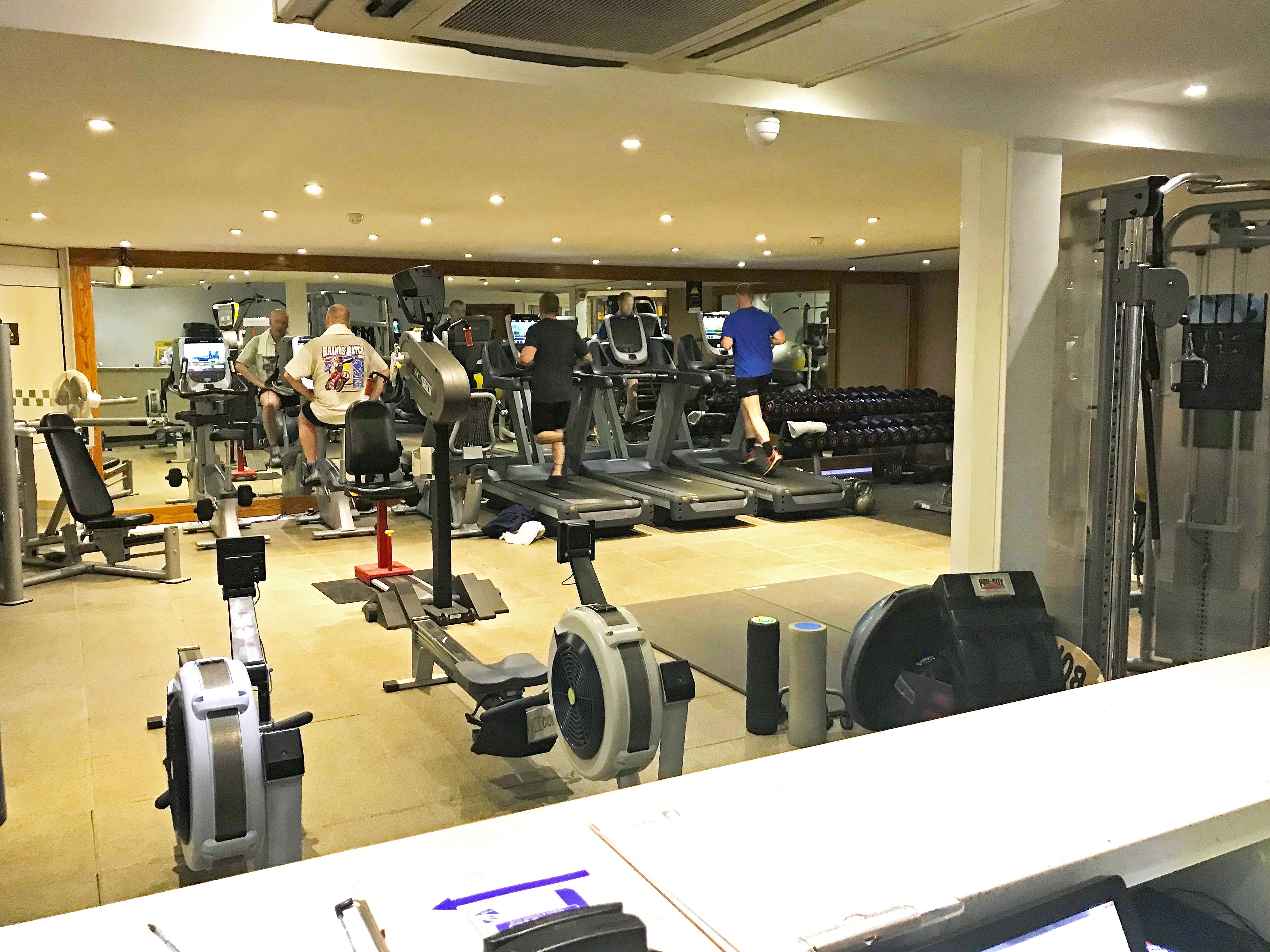 Un gimnasio con cintas de correr, máquinas de pesas y mancuernas.