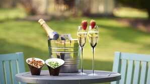 Une table ronde avec un seau en métal, deux coupes de champagne et deux bols remplis de collations.