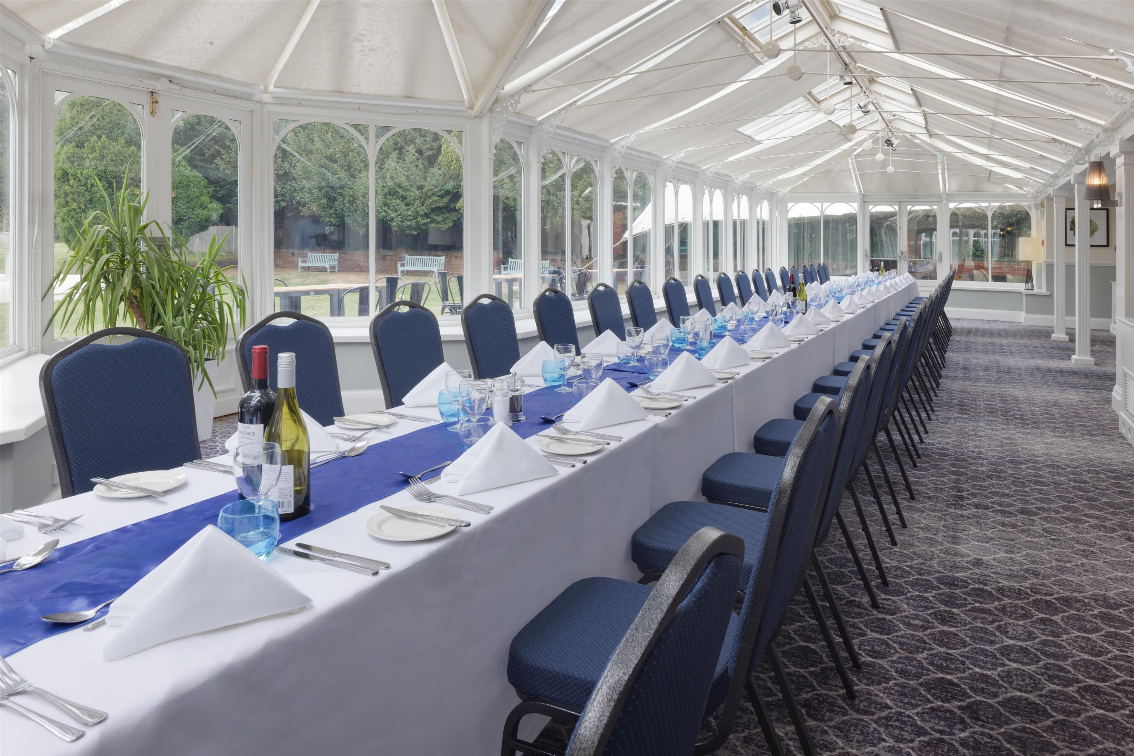 A long banquet table set for a formal event, with chairs aligned on both sides.
