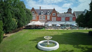 Un grand bâtiment historique doté d’une véranda, d’un espace extérieur aménagé pour s’asseoir et d’une fontaine.