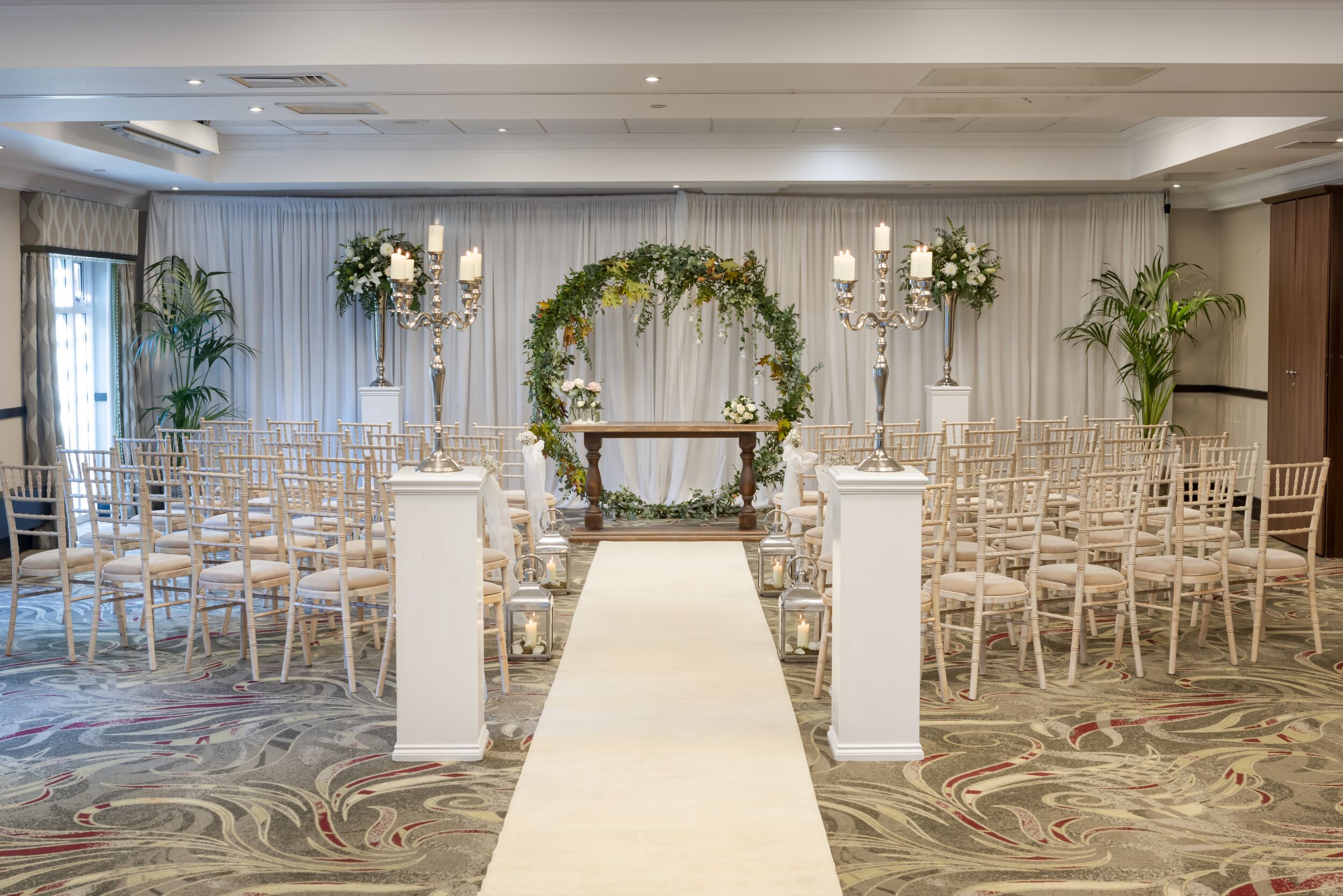 A wedding ceremony setup with a floral arch, aisle, and seating arrangement.