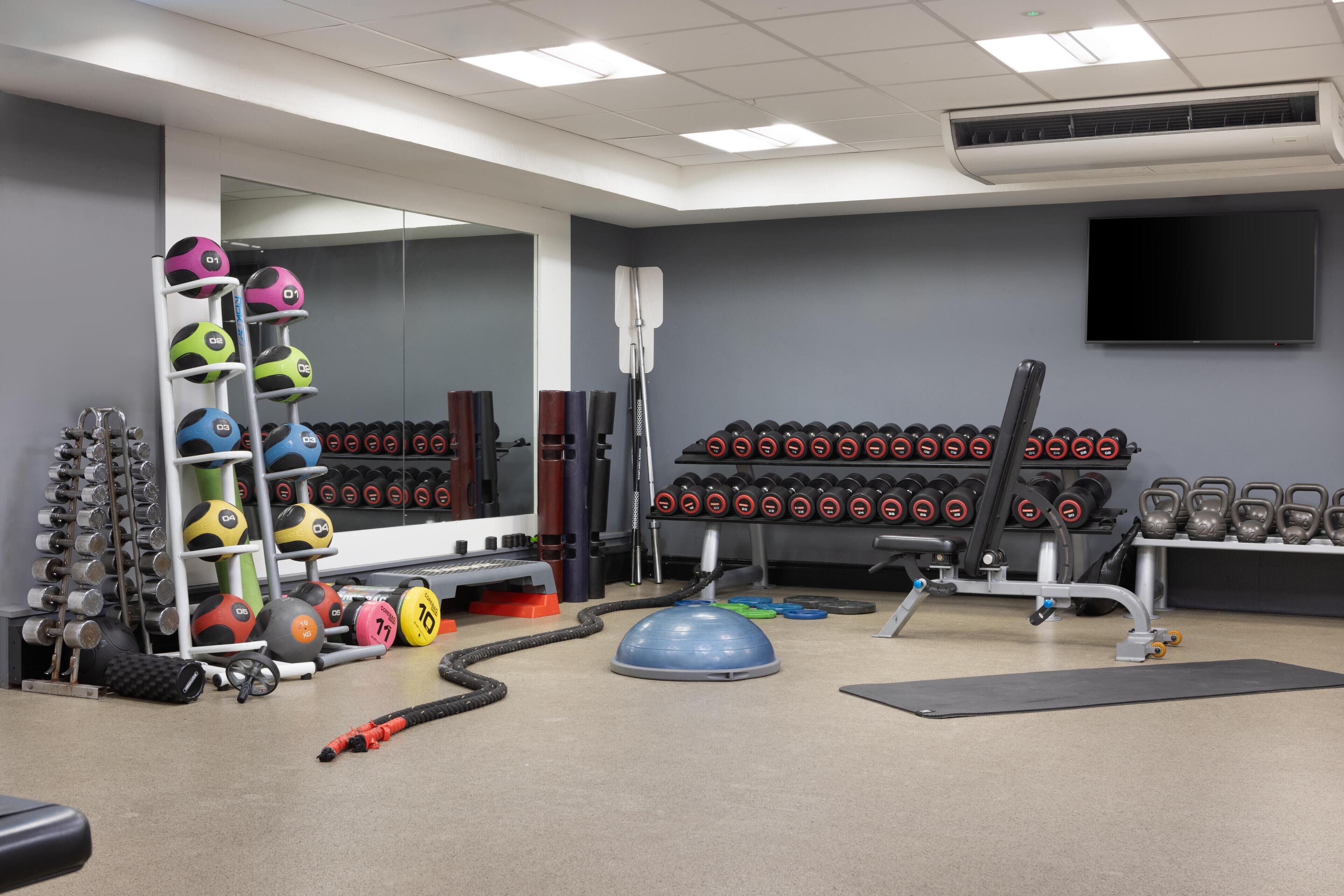 A gym with exercise equipment, a mirror, and a TV.