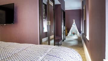 Relax in this stylish room featuring a large bed with a patterned bedspread, a wall-mounted TV, and a window with a view.