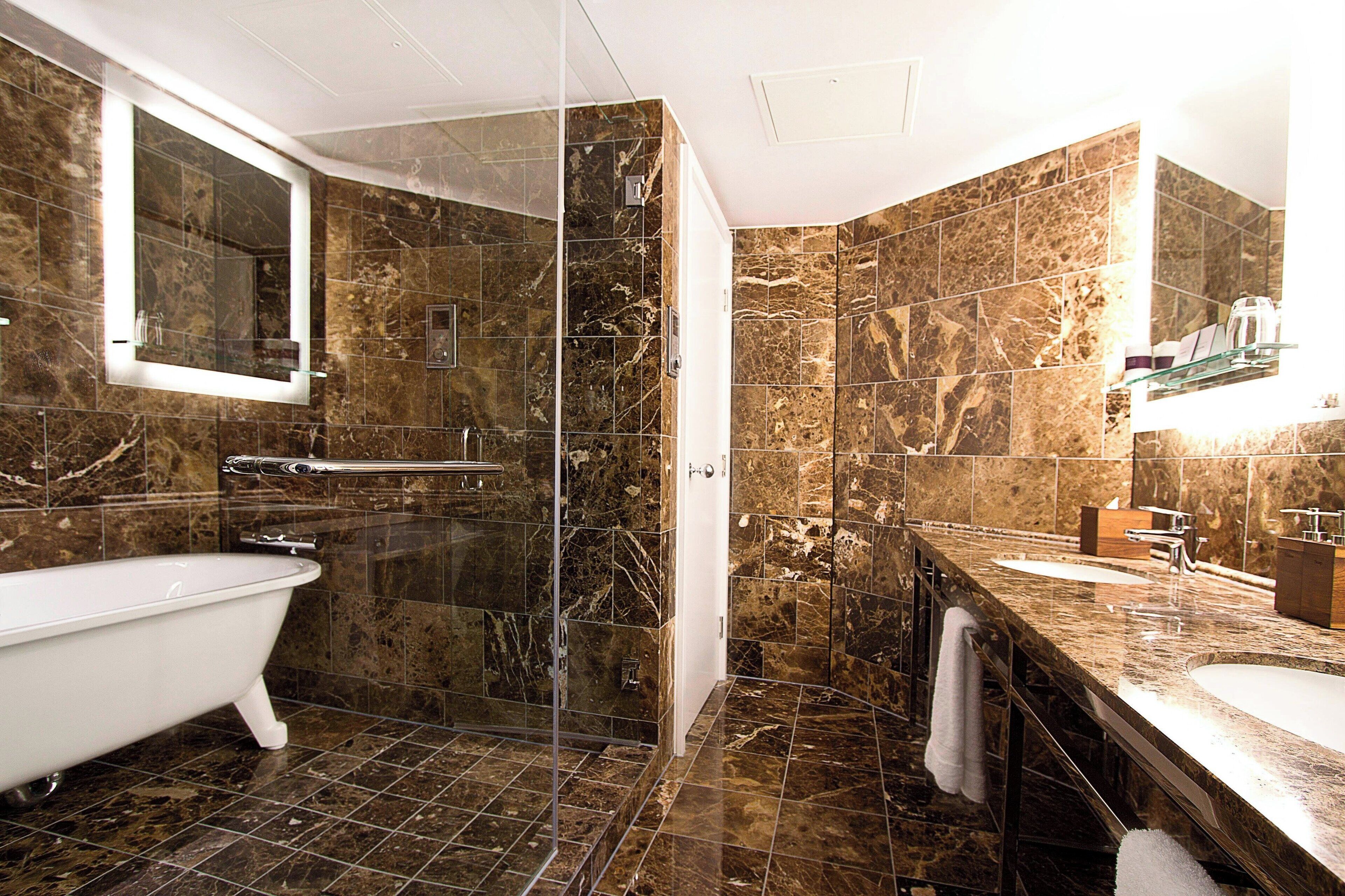 Une salle de bain avec une baignoire sur pieds, une douche à parois de verre et un meuble-lavabo avec un évier.