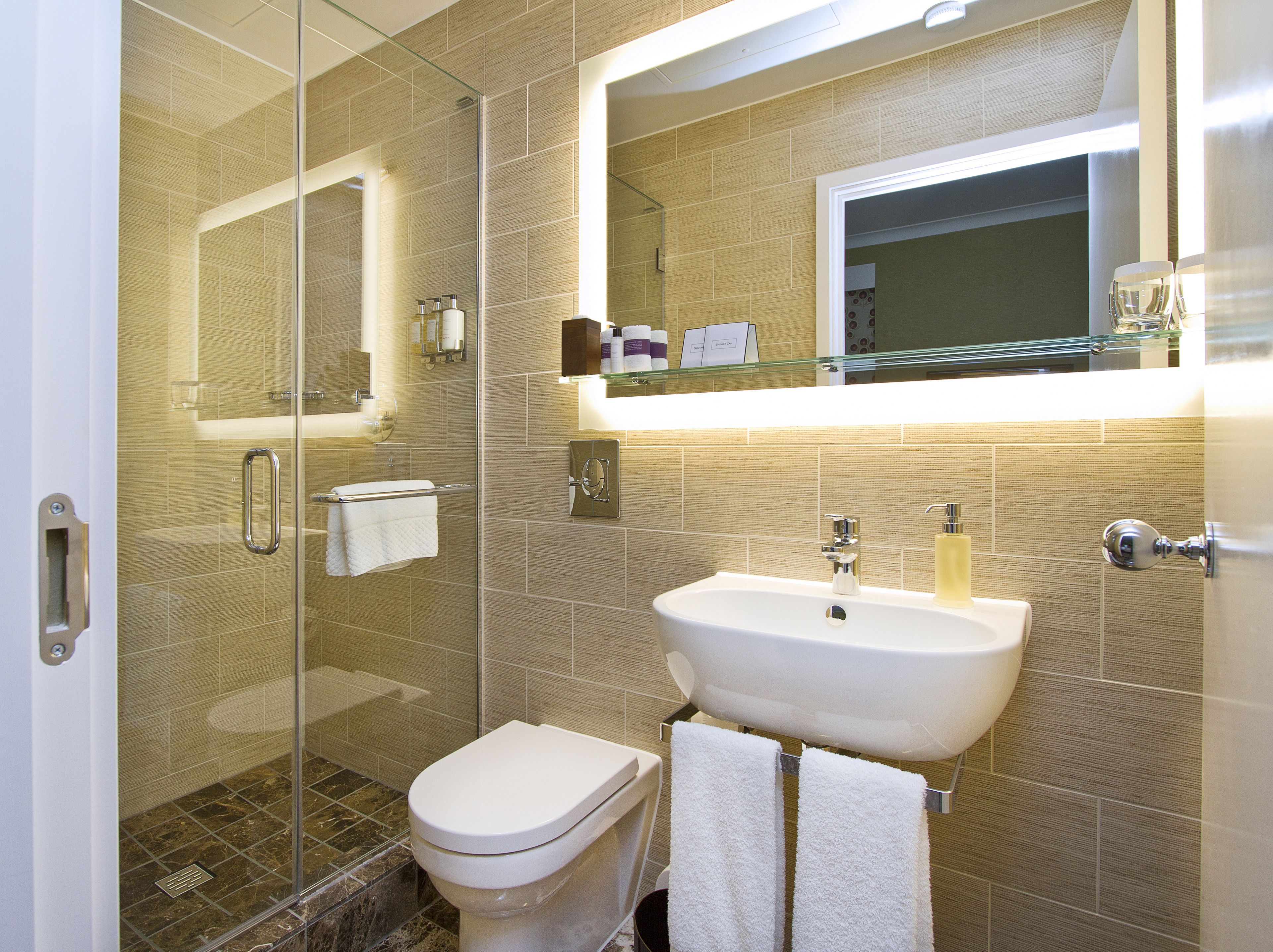 A modern bathroom with a glass shower enclosure, a white sink, and a large mirror above the mirror cabinet.