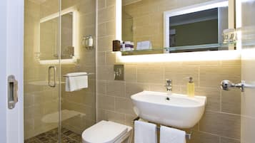 A modern bathroom with a glass shower enclosure, a white sink, and a large mirror above the mirror cabinet.