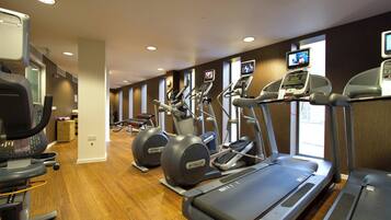 Een fitnessruimte met loopbanden, crosstrainers en een hometrainer.